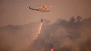 Un helicóptero arroja agua sobre un incendio forestal en la Sierra de Mijas, en la provincia de Málaga.