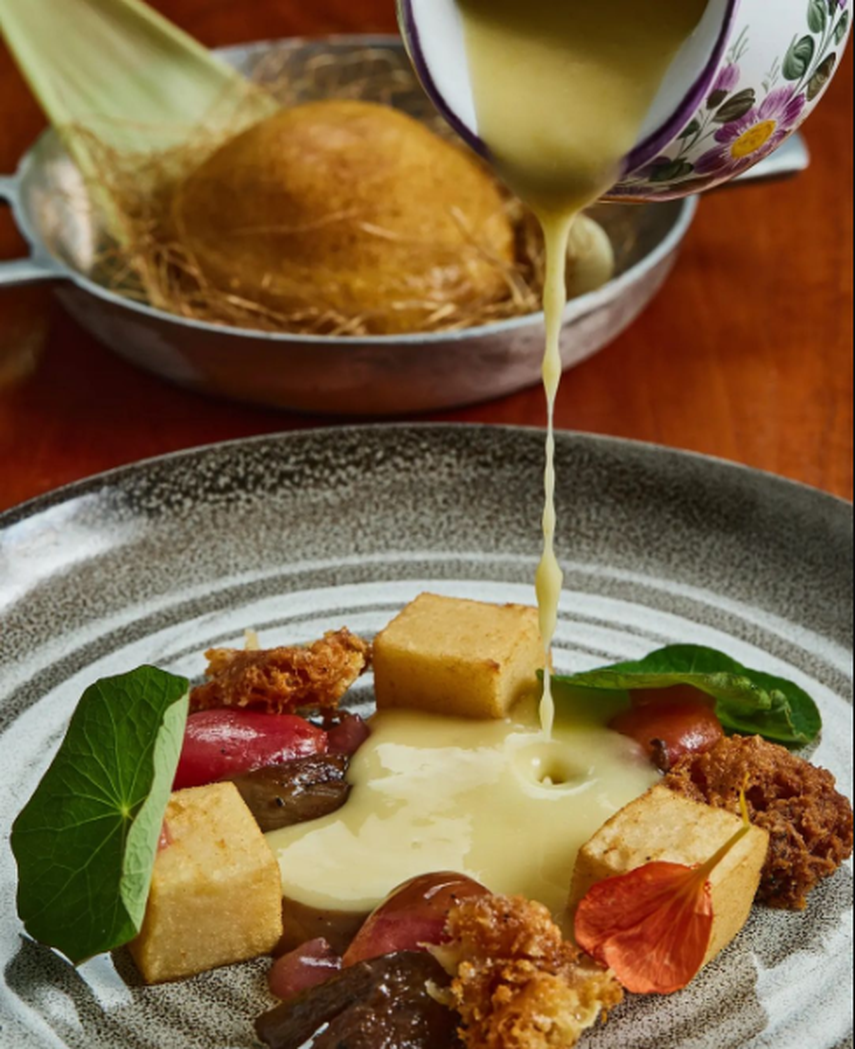 Seren de maiz nuevo (crema de maíz) tofu de habas chiricanas, tomates confitados, queso viejo frito, gel de acelgas, oyster mushrooms y demi de vegetales con café pacamara lavado, on the side, pan frito relleno de estofado de maíz y crema de pimentones.