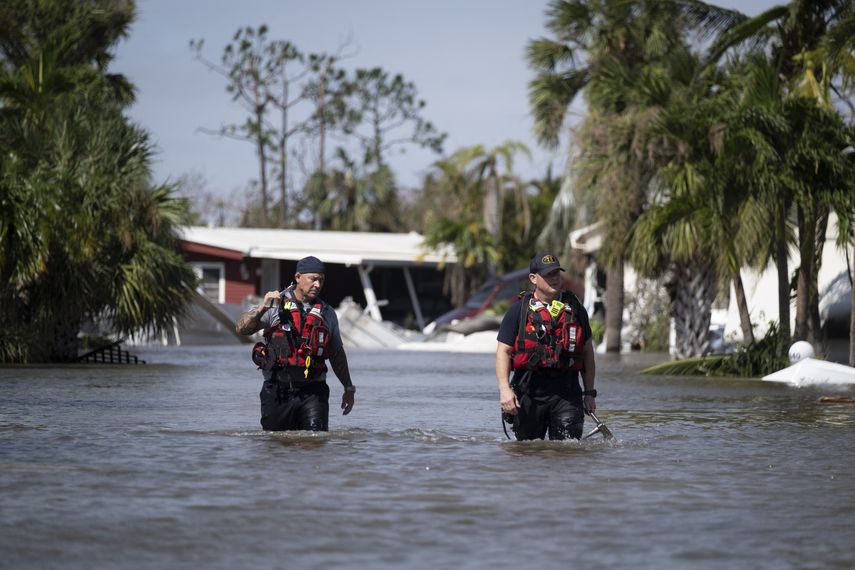 El personal de búsqueda y rescate vadea las aguas de un vecindario inundado mientras busca sobrevivientes después del huracán Ian