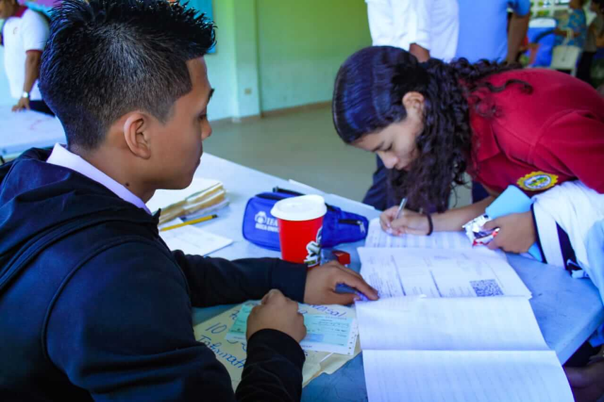 Estudiante firmando para recibir mediante cheque el pago de beca por parte del IFARHU
