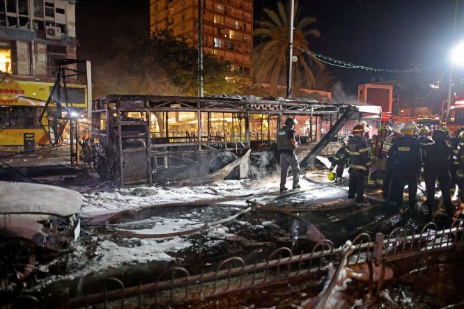 Bomberos de Israel revisan un bus calcinado tras un ataque con cohetes del grupo Hamás.