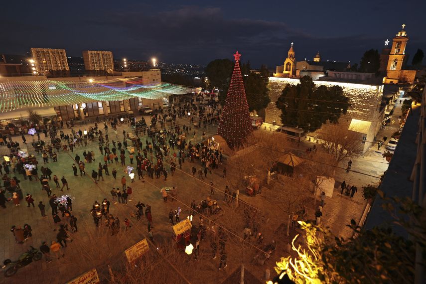 Los visitantes caminan en la Plaza del Pesebre en la víspera de Navidad fuera de la Iglesia de la Natividad