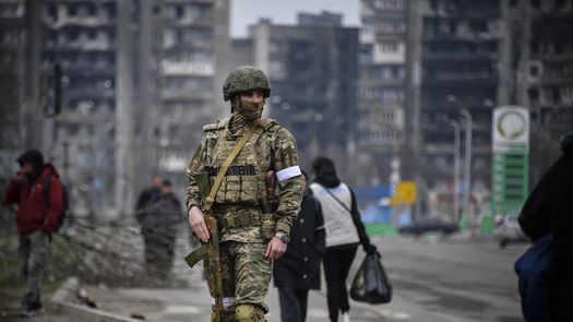 La gente pasa junto a un soldado ruso en el centro de Mariupol.