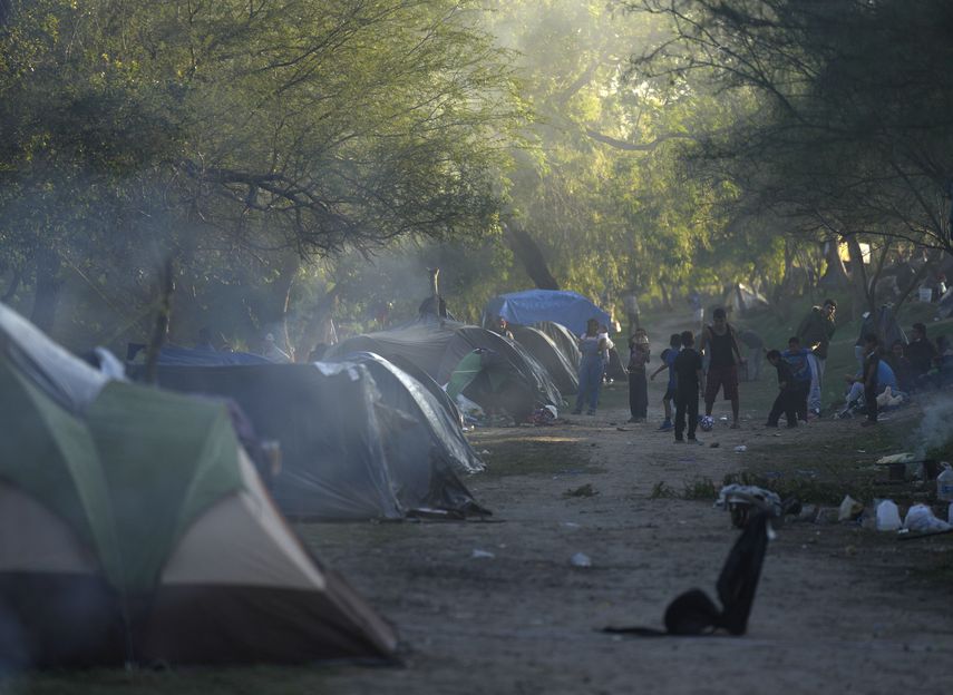 Docenas de migrantes pasan las noches en la rivera de concreto del río a la espera de algún aviso sobre un posible cambio a las restricciones al asilo impuestas en marzo de 2020.