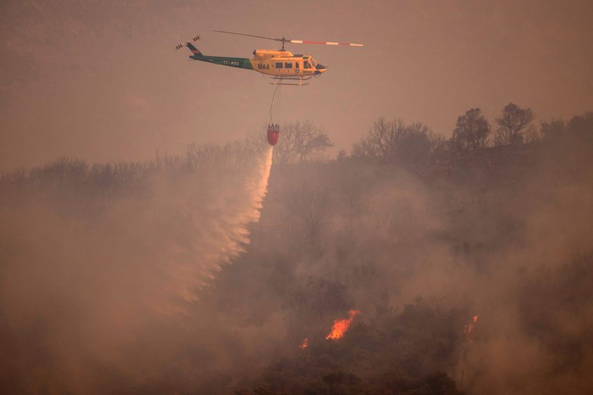 Un helicóptero arroja agua sobre un incendio forestal en la Sierra de Mijas