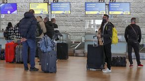 Los viajeros esperan en el mostrador de facturación antes de su vuelo de Ukraine International Airlines (UIA) a Kiev en el aeropuerto Ben Gurion de Israel.