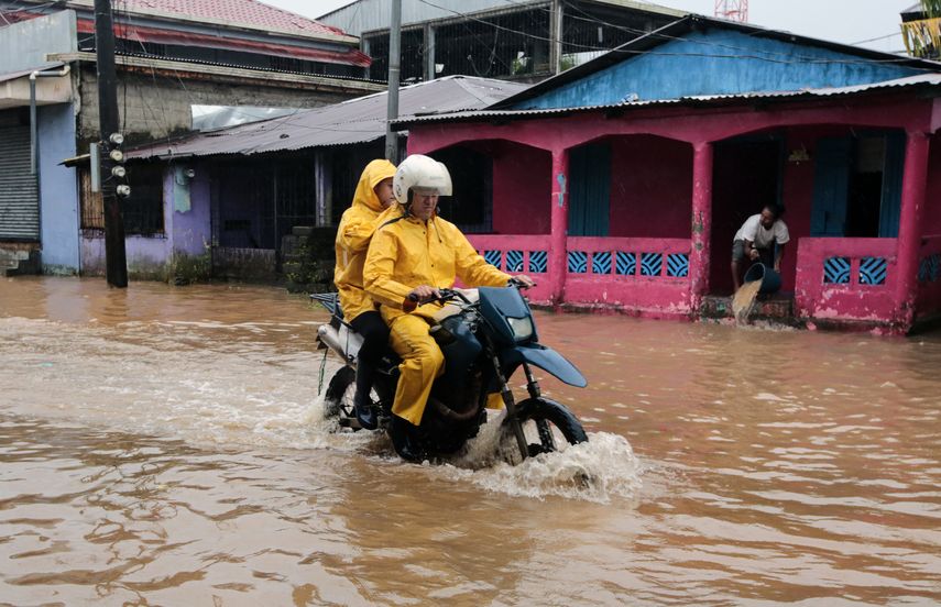 Los residentes viajan en motocicleta en una calle inundada tras el paso de la tormenta Julia en Nicaragua.