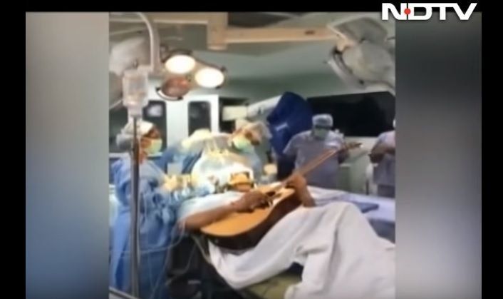 Un músico indio toca la guitarra mientras le operan el cerebro