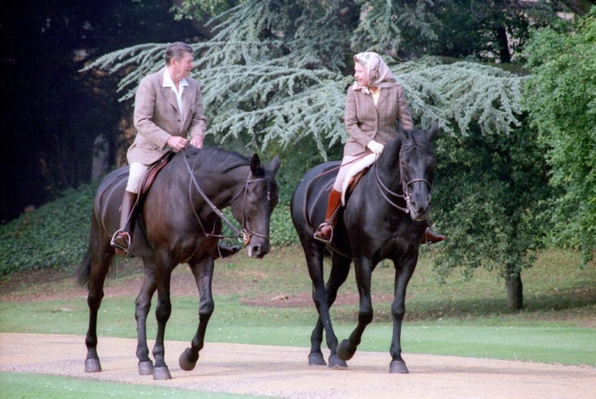 La Reina Isabel II montando a caballo junto a Ronald Reagan en su visita al castillo de Windsor en 1982.