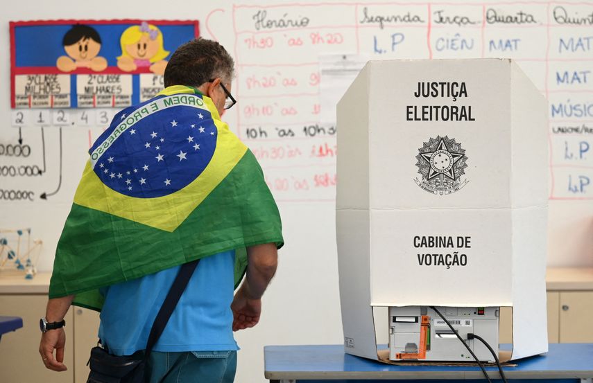 Un hombre con una bandera nacional de Brasil sobre sus hombros vota en un colegio electoral en Brasilia