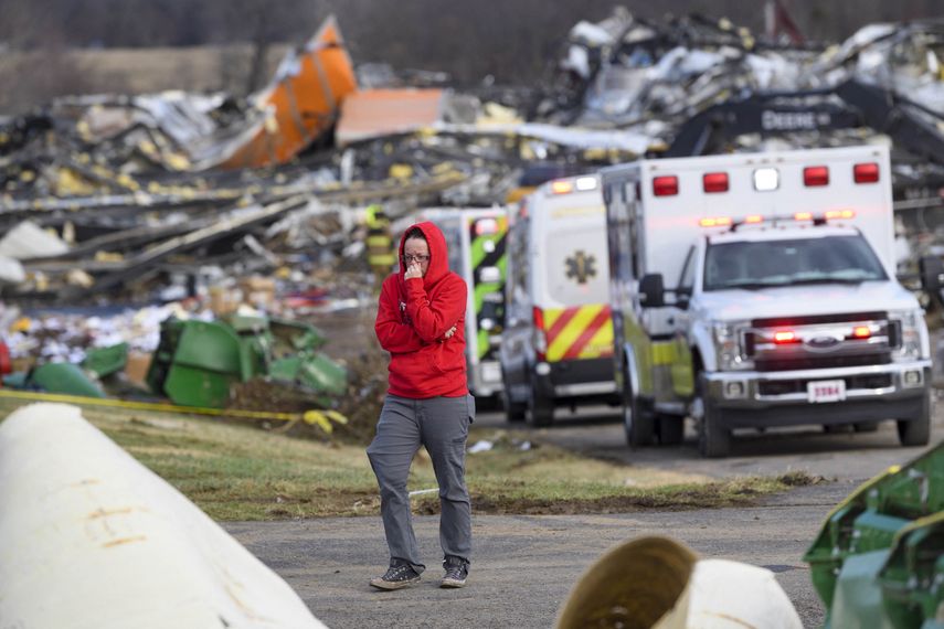 Una mujer se aleja de una fila de ambulancias en la propiedad de Mayfield Consumer Products Candle Factory después de que fuera destruida por un tornado