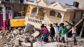 Personas recuperan cosas que les puedan servir durante el  trabajo de integrantes de la brigada Rescate Internacional Topos en un área afectada por el terremoto , en Les Cayes, Haití.