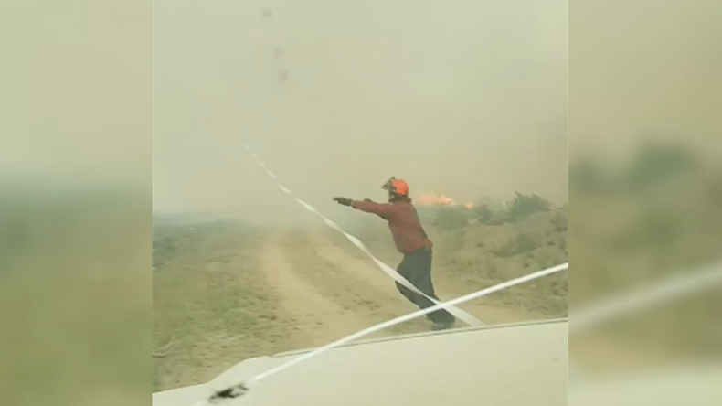 Bomberos canadienses luchan por controlar sus mangueras en un tornado de fuego