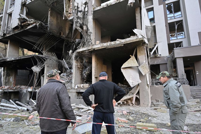 La gente se para frente a un edificio dañado luego de los ataques rusos en Kiev.