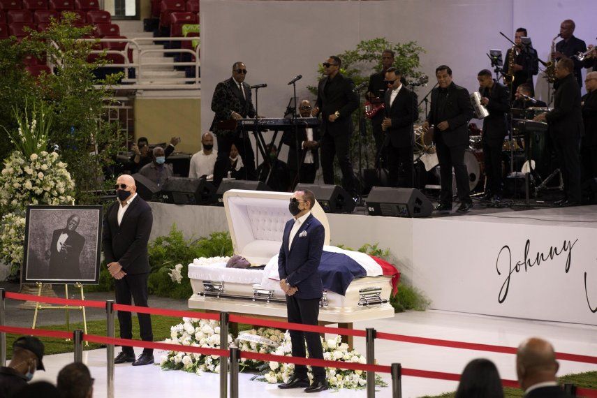 Los artistas dominicanos Hermanos Rosario permanecen junto al cuerpo del merenguero dominicano Johnny Ventura.