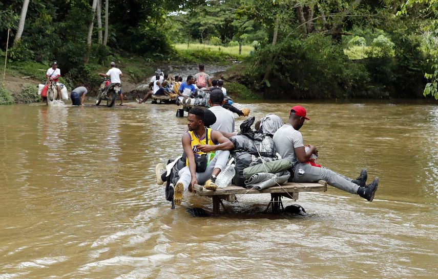 Migrantes haitianos cruzan el río Guati durante su traslado a un campamento en el que dormirán para iniciar su viaje hacia el Tapón del Darién.