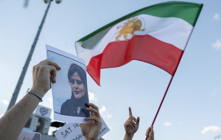 La bandera de Irán ondea junto a una foto de la joven Mahsa Amini.