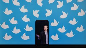 Un teléfono celular muestra una foto de Elon Musk colocada en un monitor de computadora lleno de logotipos de Twitter.