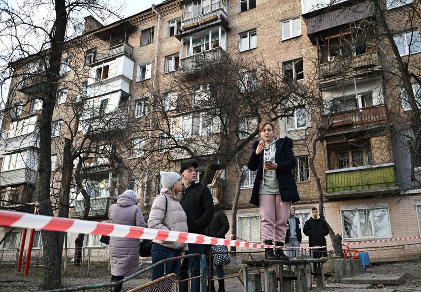 Los residentes miran las casas residenciales que fueron parcialmente destruidas por un ataque ruso en la capital de Ucrania.