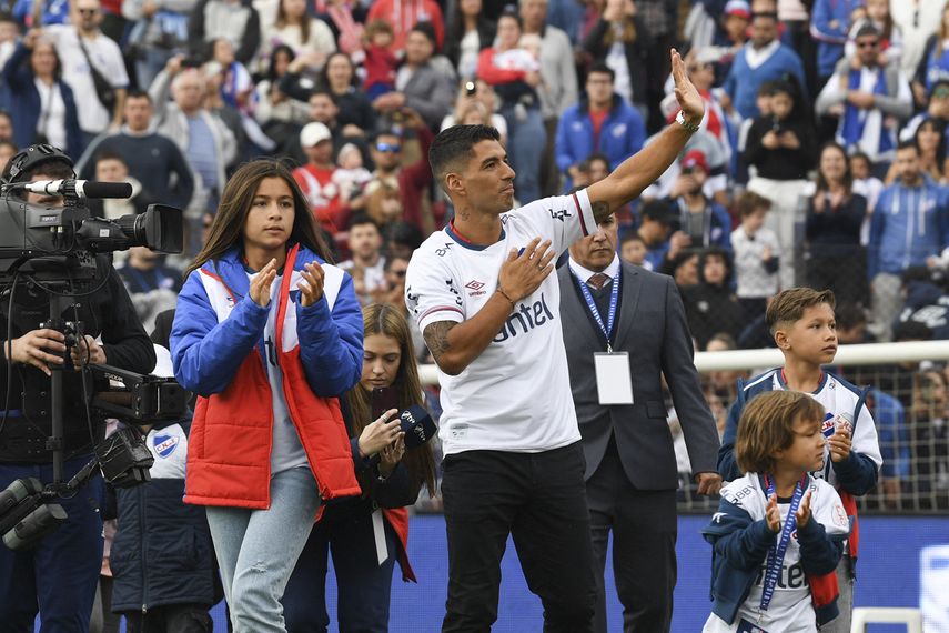 El delantero uruguayo Luis Suárez saluda a la multitud junto a sus hijos durante su presentación como nuevo jugador de Nacional de Uruguay.