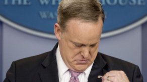 Spicer da conferencia con el pin de la bandera de cabeza