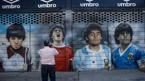 Un hombre toma una foto a un mural sobre Diego Armando Maradona en el estadio de Argentinos Juniors.