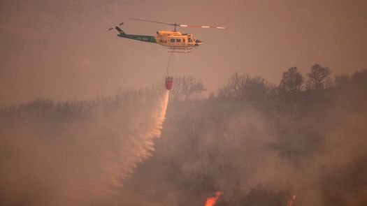 Un helicóptero arroja agua sobre un incendio forestal en la Sierra de Mijas, en la provincia de Málaga.
