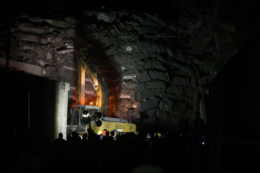 Funcionarios de rescate se encuentran cerca de una excavadora en el sitio de un edificio derrumbado en Lagos