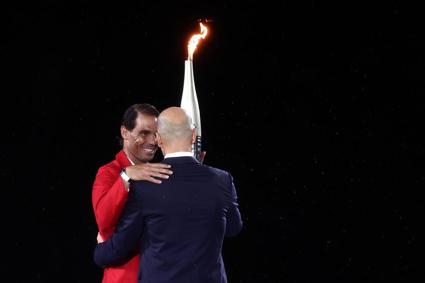 Rafael Nadal recibiendo la llama olímpica de Zinedine Zidane en la inauguración de las Olimpiadas 2024.