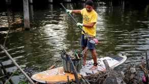 Atrapando plástico en una tabla de surf en los inmundos canales de Bangkok