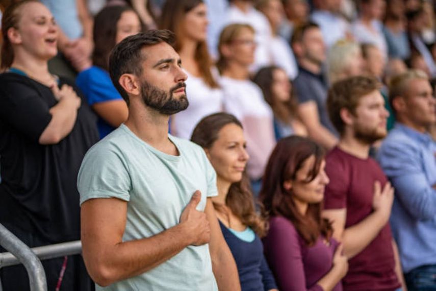 Personas&nbsp;de pie cantando el Himno Nacional más boniito según la Ai