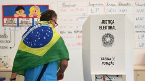 Un hombre con una bandera nacional de Brasil sobre sus hombros vota en un colegio electoral en Brasilia, durante la segunda vuelta de las elecciones presidenciales.