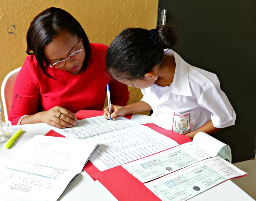 Estudiante firmando para recibir el pago de beca por el Ifarhu