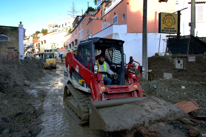 Un hombre usa un tractor para quitar el barro de una calle en Casamicciola