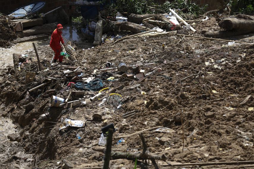 Un bombero quita lodo mientras busca víctimas de un deslizamiento de tierra en la comunidad de Bola de Ouro