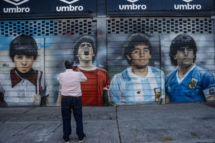 Un hombre toma una foto a un mural sobre Diego Armando Maradona en el estadio de Argentinos Juniors.